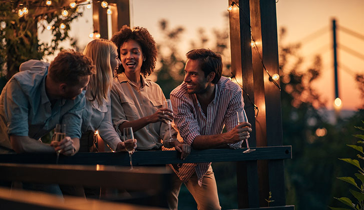 Two couples enjoying the view at the terrace and drinking wine
